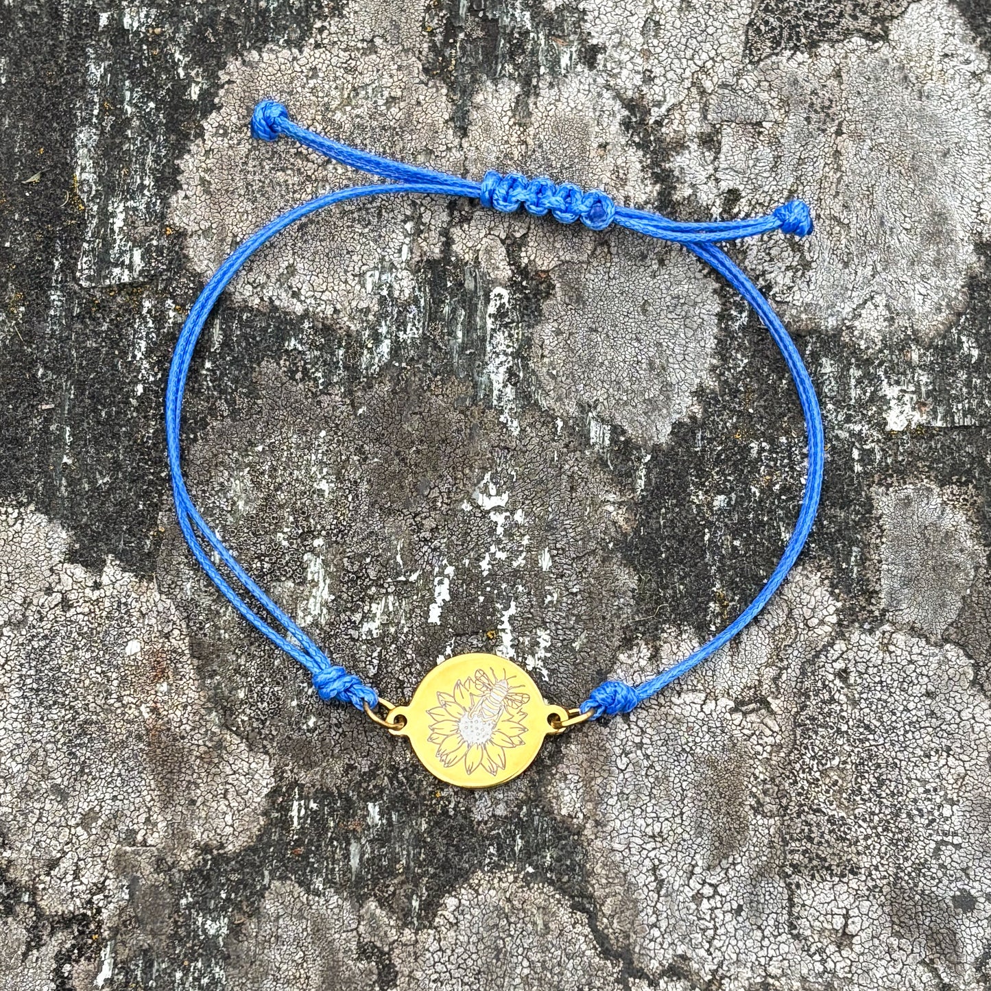 Bumble bee on sunflower on 21mm round golden on thin cord blue