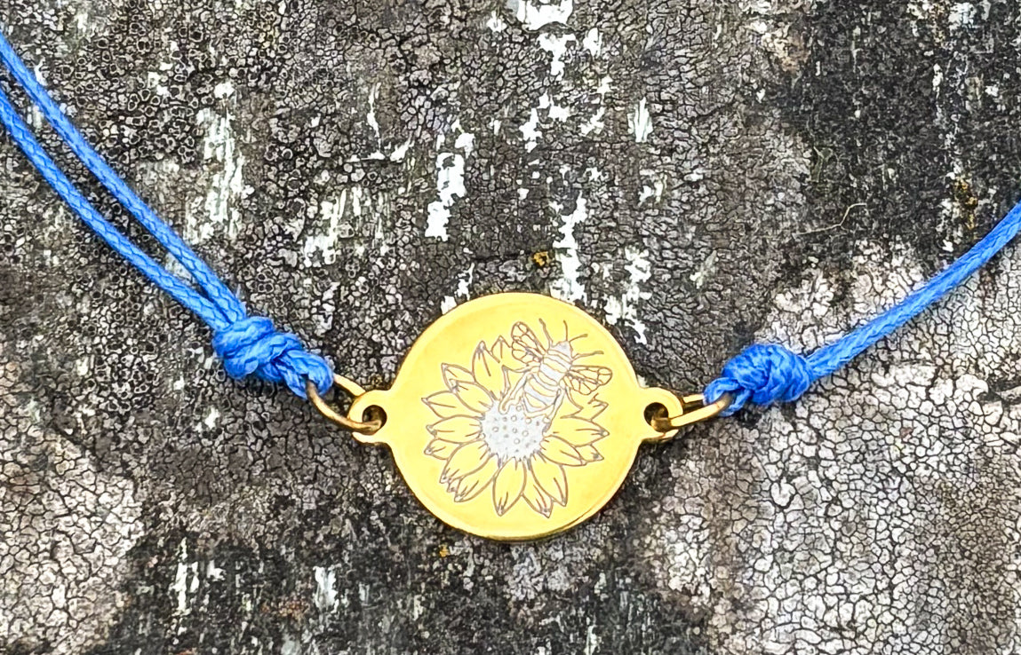 Bumble bee on sunflower on 21mm round golden on thin cord blue